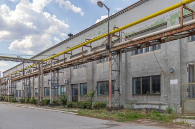 Yellow Gas Pipe and Silver Heating Steam Pipeline at Rusty Industrial Structure