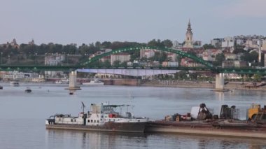 Belgrade, Serbia - August 16, 2022: Tug Boat Moored at Sava River Old Arch Bridge Summer Evening.