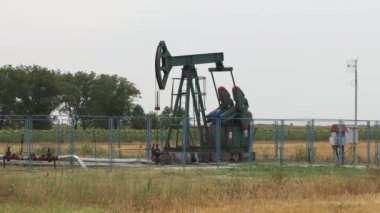 Pump Jack Pumping Oil Well at Farm Field