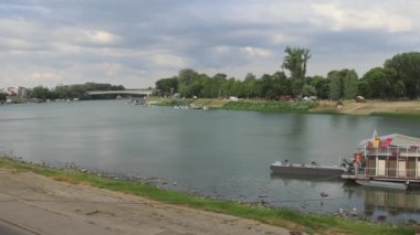 Szeged, Macaristan - 01 Ağustos 2022: Nehir Tisza ve Belvarosi Köprüsü Yaz Günü 'nde Çamurlu Teknelerle Pontoon Rıhtımı.