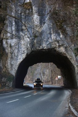 Küçük bir tünelden geçerken farları yanan bir araba..