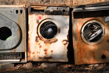 Abandoned rusty washing machines in nature.