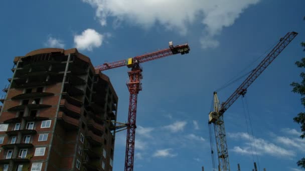 Bouw kraan werken tegen de blauwe hemel en wolken — Stockvideo