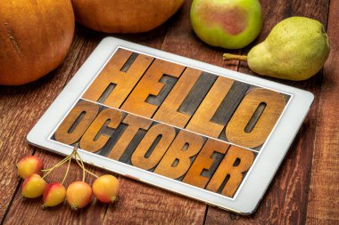 Merhaba October. Kabak ve meyveli dijital tablet ekranında eski harf harfleriyle yazılmış soyut tahta bloklar.