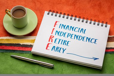 Yangın kısaltması - finansal bağımsızlık, erken emeklilik, eskiz defterinde bir fincan kahve ile renkli soyut kağıt manzarasına karşı el yazısı