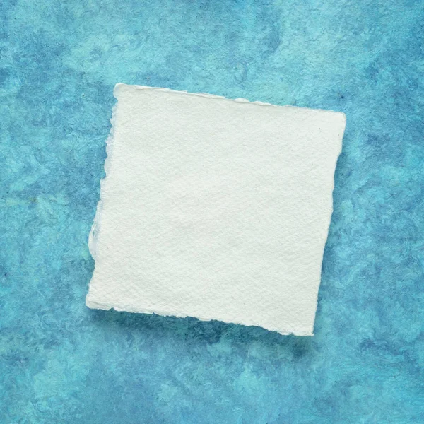 Mały Kwadratowy Arkusz Białego Papieru Khadi Przeciwko Niebieskiemu Papierowi Korą — Zdjęcie stockowe