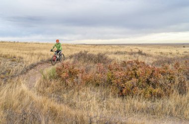Son sınıf bisikletçi, Colorado ovasında tek bir patika üzerinde dağ bisikleti sürüyor - Soapstone Prairie Natural Area - Geçen sonbahar renkleri Ekim sonlarında