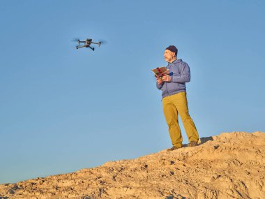 Grover, CO, ABD - 22 Kasım 2021: İPad tableti ve radyo denetçisi kıdemli erkek pilot, DJI tarafından çöl bölgesinde geliştirilmiş, katlanabilir bir tüketici dronu olan Mavic 3 'ü işletiyor.