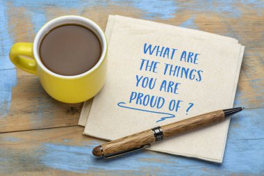 Gurur duyduğun şeyler nelerdir? Peçeteye bir fincan kahve ile el yazısı. Başarıların ve başarıların gözden geçirilmesi, kişisel gelişim kavramı.