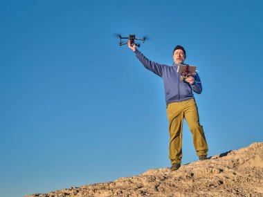 Grover, CO, ABD - 22 Kasım 2021: İPad tableti ve radyo denetçisi kıdemli erkek pilot, DJI tarafından çöl bölgesinde geliştirilmiş, katlanabilir bir tüketici dronu olan Mavic 3 'ü işletiyor.