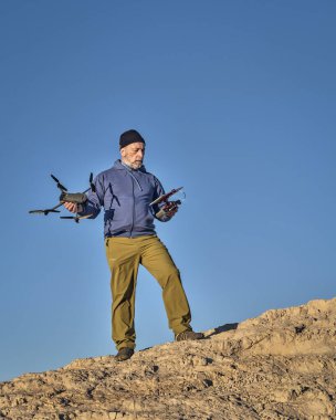 Grover, CO, ABD - 22 Kasım 2021: İPad tableti ve radyo denetçisi kıdemli erkek pilot, DJI tarafından çöl bölgesinde geliştirilmiş, katlanabilir bir tüketici dronu olan Mavic 3 'ü işletiyor.