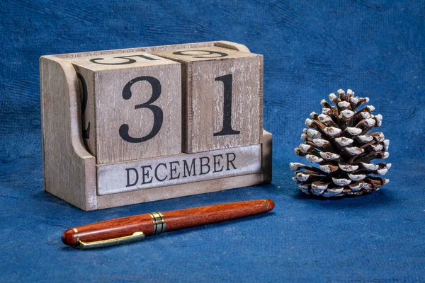 装飾的な霜松のコーン 今年の最終日 新年のコンセプトとグリーティングカードを持つ素朴な木のブロックカレンダーで12月31日の日付 — ストック写真