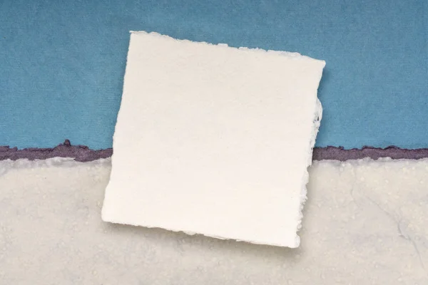 Mały Kwadratowy Arkusz Białego Papieru Khadi Przeciwko Niebieskiemu Papierowi Szmatławemu — Zdjęcie stockowe