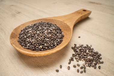 Tahta kaşıkta siyah chia tohumları, ahşap masaya karşı, makro shot.