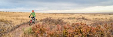 Son sınıf bisikletçi Colorado ovasında tek bir patika üzerinde dağ bisikleti sürüyor - Soapstone Prairie Natural Area Geçen sonbahar renkleri, panoramik web afişi