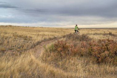 senior cyclist is riding a mountain bike on a single track trail in Colorado prairie - Soapstone Prairie Natural Area with last fall colors in late October