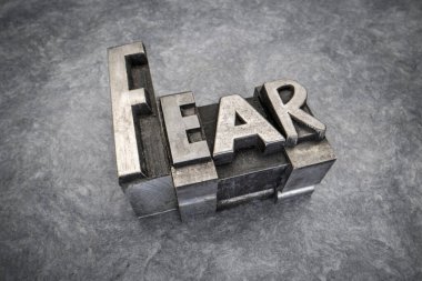 fear word abstract in gritty vintage letterpress metal types, mixed fonts against handmade bark paper, negative emotions concept