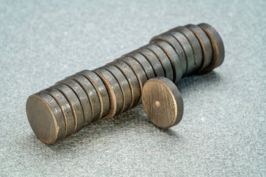 stack of small round ceramic ferrite magnets on textured gray  paper
