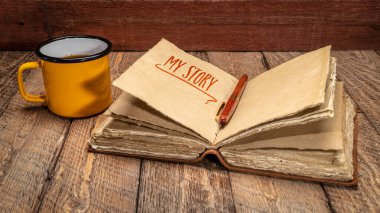 my story - handwriting in a retro  leather-bound journal with decked edge handmade paper pages and cup of tea on rustic wood, journaling concept clipart