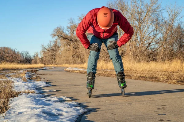 疲れている男性スケーターは休憩を取っています コロラド州のプードル川沿いの舗装された自転車道でインラインスケート 日没で秋や冬の風景 — ストック写真