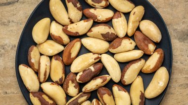 Dokulu el yapımı kağıt arka plana karşı siyah bir plaka üzerinde Brezilyalı fındık