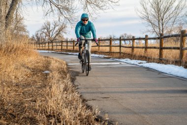 Windsor, CO, ABD - 9 Şubat 2022 - Erkek bisikletçi, kışın Poudre Nehri Koridoru üzerinde bisiklet sürüyor veya kuzey Colorado 'da sonbahar manzarası.
