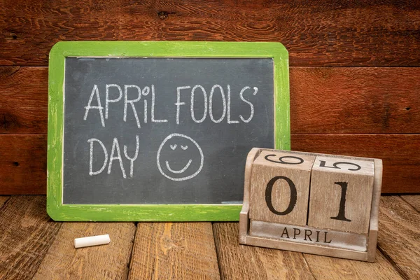 4月の愚か者の日 木製のカレンダーとヴィンテージスレートの黒板に白いチョークの手書き — ストック写真