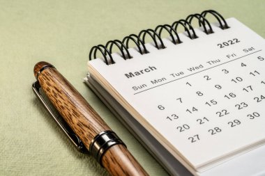 Mart 2022 - biçimlendirilmiş kağıt, zaman ve iş konseptine karşı şık bir kalemle spiral masaüstü takvimi