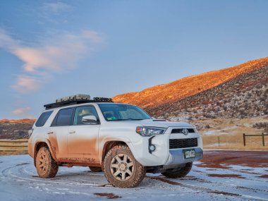 Fort Collins, CO, ABD - 17 Şubat 2022: Kirli Toyota 4Runner SUV (2016 Trail modeli) Colorado eteklerinde kış günbatımında çamurlu bir çiftlik yolunda.