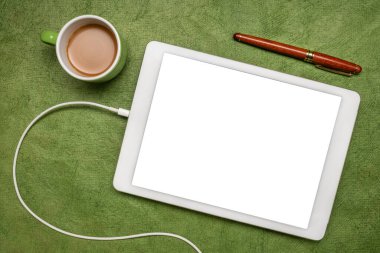 Boş bir izole ekran (kırpma yolu dahil) ile dijital tablet modeli, yeşil desenli kağıt üzerinde bir fincan kahve ile düz yatıyordu