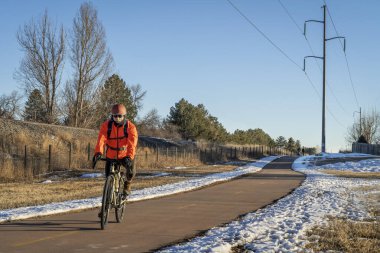 Son sınıf erkek bisikletçi Fort Collins, Colorado 'da kış manzarasında bisiklet turu yapıyor. Demiryolu ve elektrik hattı boyunca elektrik hattı var.