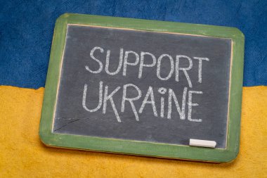 Ukrayna 'yı destekleyin - Ukrayna ulusal bayrağı mavi ve sarı renkli kağıt soyutlamasına karşı eski bir tahta üzerinde beyaz tebeşirle yazı