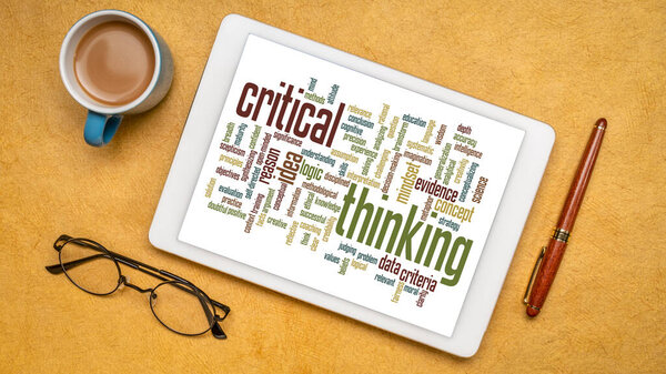 critical thinking word cloud on a digital tablet, flat lay with a cup of coffee
