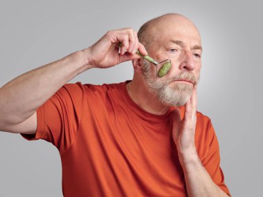 Son sınıf öğrencisi yüz masajı için yeşim taşı silindiri kullanıyor.