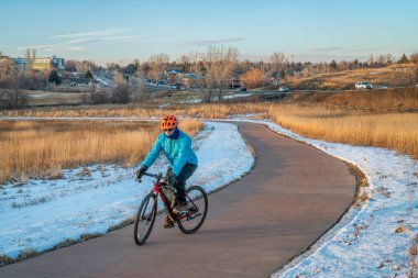 Fort Collins, Colorado 'da çakıl bisikleti süren bir bisikletçiyle bisiklet parkında kış günbatımı.