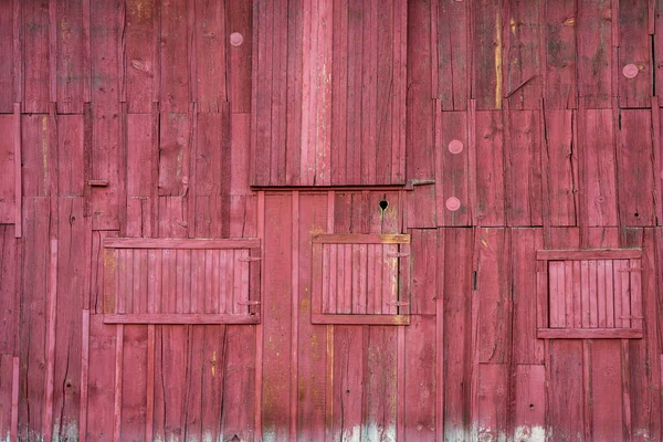 風化した赤い塗装納屋の壁 素朴な木の背景と複数のドアや窓と質感 — ストック写真