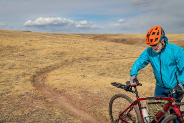 Colorado eteklerinde tek bir patika üzerinde çakıllı bisikletli erkek bisikletçi ilkbahar manzarası, Soapstone Çayır Doğal Alanı