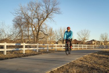 Son sınıf erkek bisikletçi, sonbaharda ya da kış mevsiminde Kuzey Colorado 'da WIndsor yakınlarındaki Poudre River Trail' de sayısız bisiklet yolundan birinde çakıl bisikleti sürüyor.