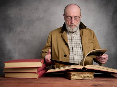 Sakallı, yaşlı bir adamın eski kitapları okuyup gezerken sıradan bir portresi.