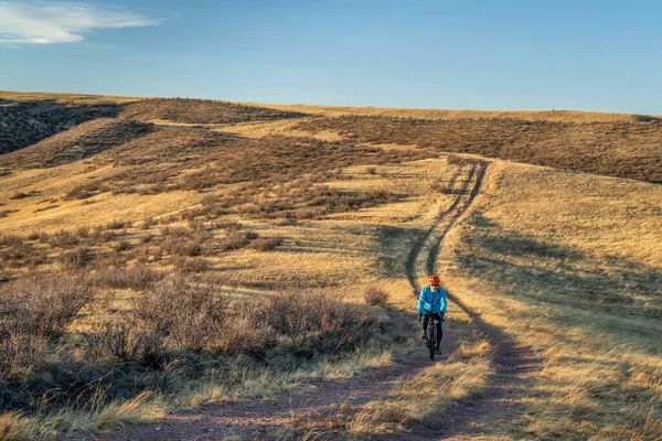 位于科罗拉多州索普斯通草原自然区的早春风景中 一位骑自行车的资深男性骑手正在一条小径上骑着一辆砾石自行车 — 图库照片