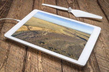 Colorado 'da ilkbaharın başlarında kuru bir dere, yalnız bir ağaç ve sığır patikası, dijital tablet üzerindeki hava görüntülerini gözden geçirir.