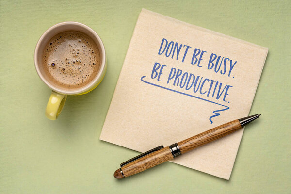 Don't be busy. Be productive. Handwriting on a napkin with a cup of coffee. Business and productivity concept.
