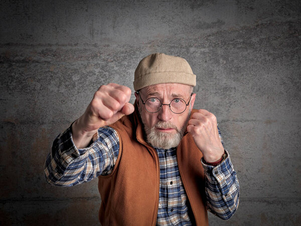 Старший, бородатый, напуганный человек в боксе пытается защитить себя