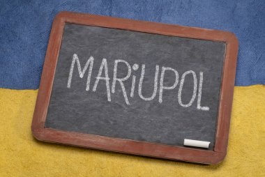 Mariupol beyaz tebeşir metni Ukrayna 'nın mavi ve sarı, kahraman şehri Ukrayna bayrağı renginde kağıt soyutlamasına karşı eski bir kara tahta üzerinde