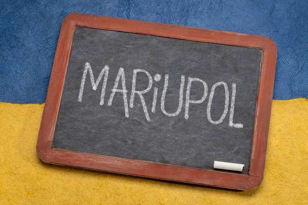 Mariupol beyaz tebeşir metni Ukrayna 'nın mavi ve sarı, kahraman şehri Ukrayna bayrağı renginde kağıt soyutlamasına karşı eski bir kara tahta üzerinde