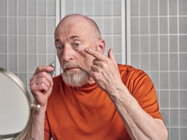 Son sınıf öğrencisi gözlerinin altına retinol kremi sürüyor. Cilt bakımı ve erkek konsepti.