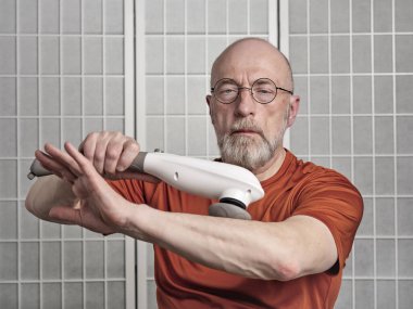 Son sınıf öğrencisinin portresi. El vibratörü, tenis dirsek terapisi ve kendine bakım konseptiyle koluna masaj yapıyor.