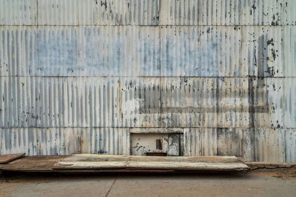 粗糙的城市或工业背景和质感 被风化的波纹金属板覆盖的建筑墙 地板上腐烂的木板 — 图库照片