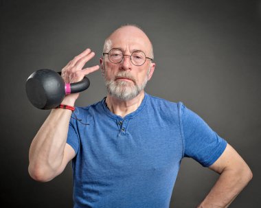 Son sınıf öğrencisi (60 'ların sonunda) demir kettlebell, aktif son sınıf ve fitness konsepti ile egzersiz yapıyor