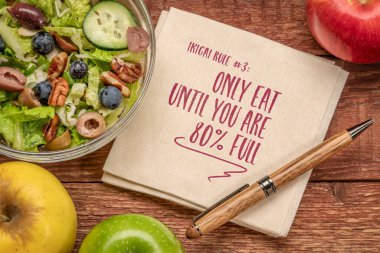 Sadece% 80 dolana kadar yiyin, ikigai kuralı, salatalı bir peçeteye ilham verici bir not, sağlıklı beslenme ve yaşam tarzı konsepti.